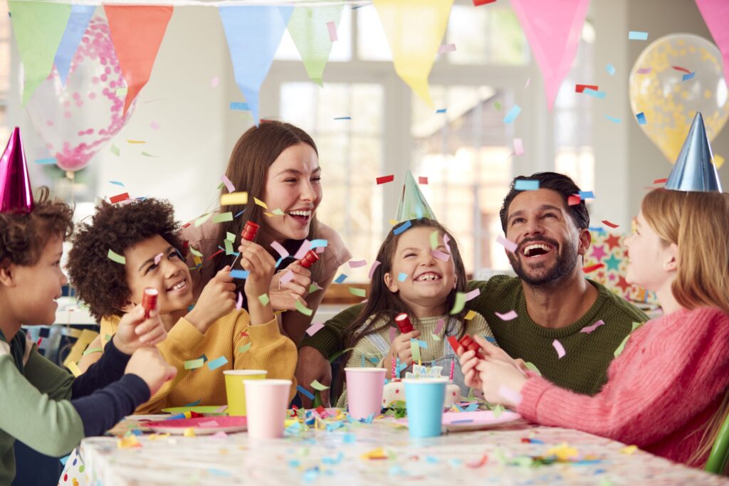 girl with parents friends home celebrating birthday firing confetti poppers party scaled 1 Home.